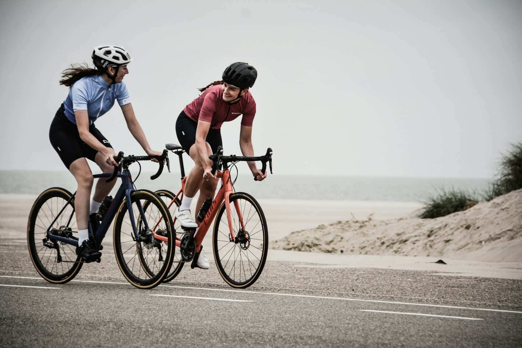 Two riders mid-effort on a coastal road