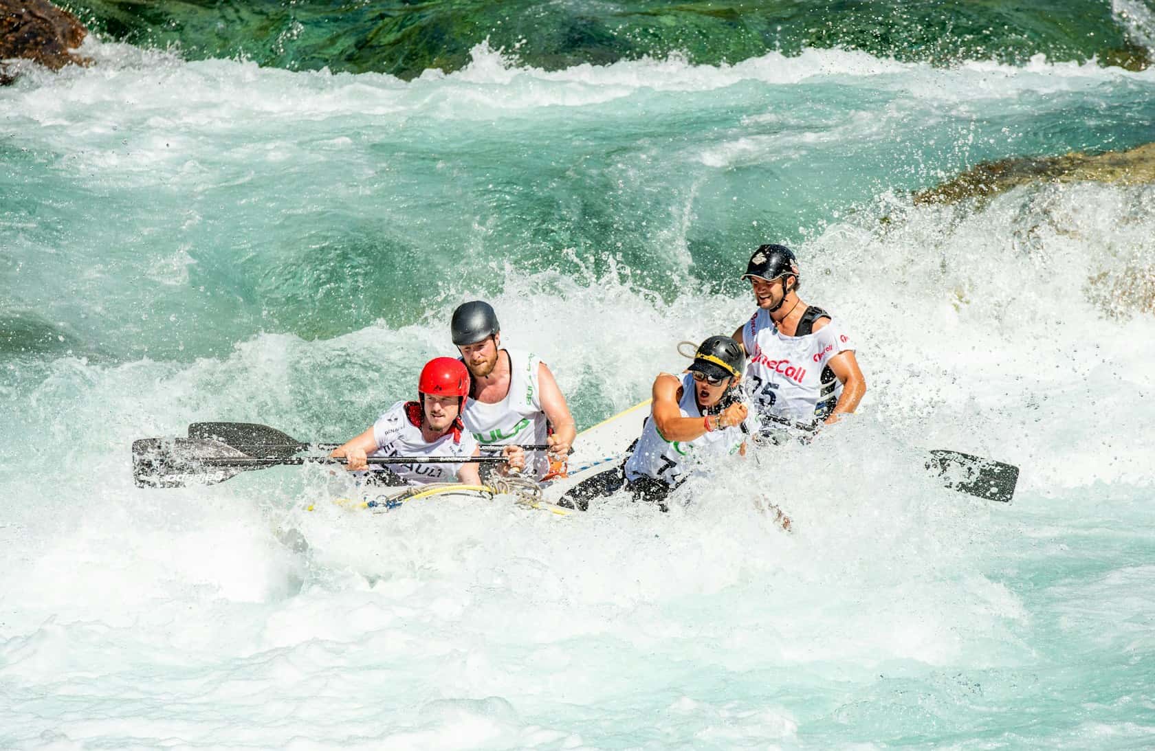 A raft crew mid-rapid, spray flying