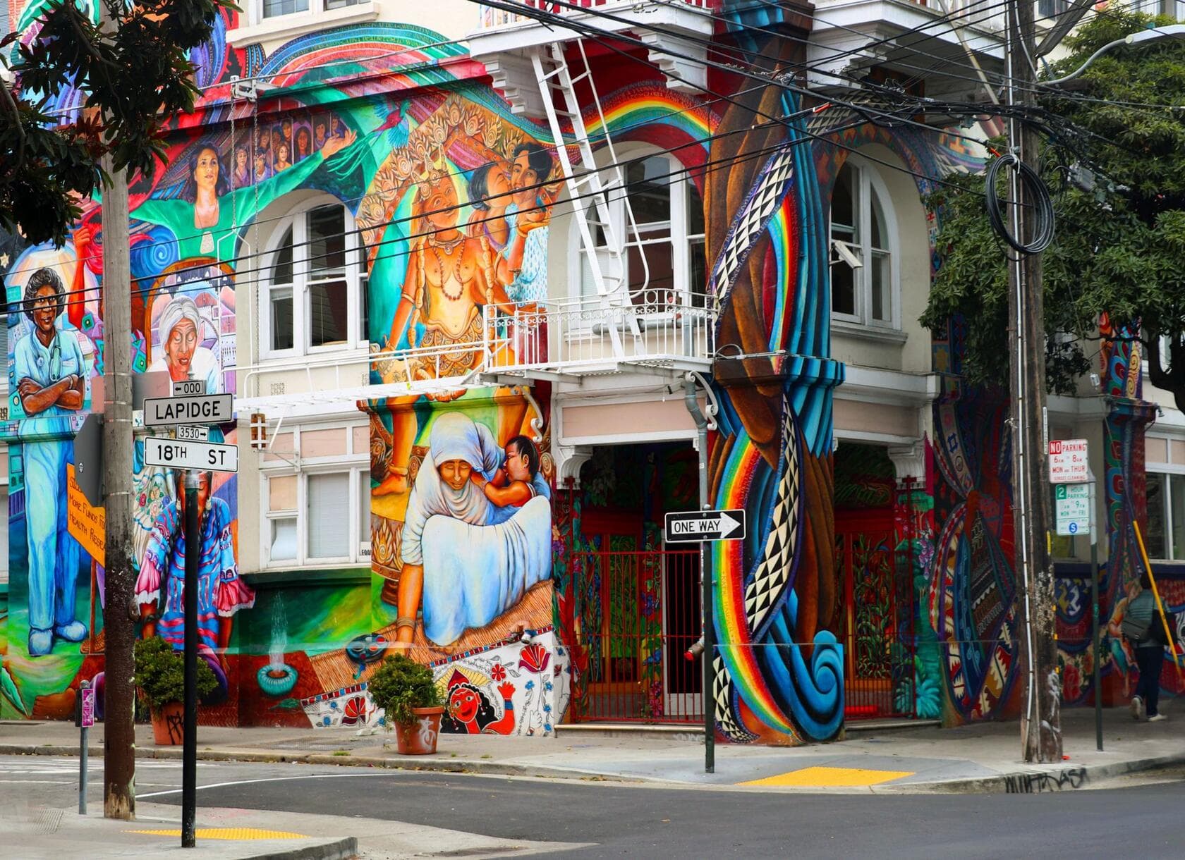 A mural-covered corner building on a city street-art route